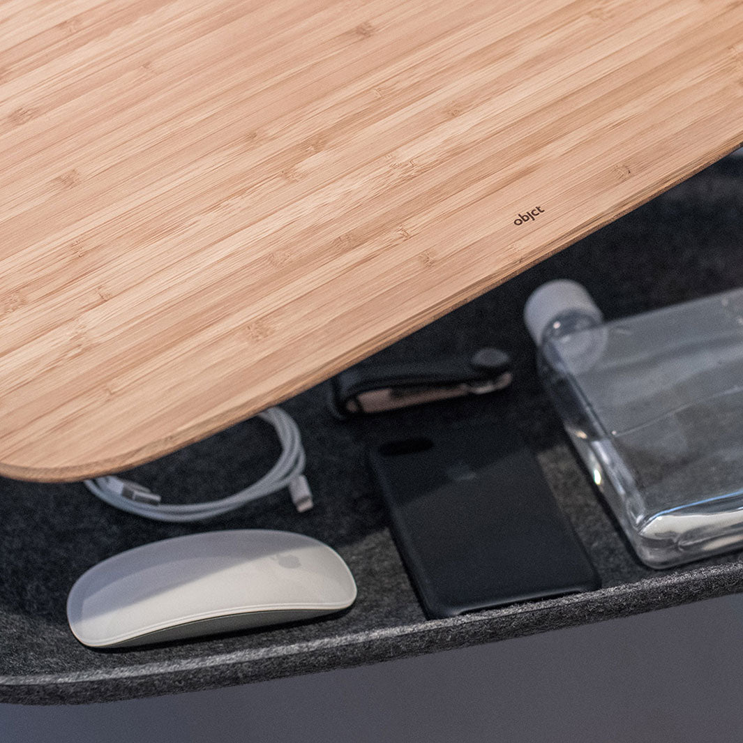 Closeup detail of LAPOD lap desk by objct co bamboo tray table with felt storage compartment open showing work accessories like USB cable, mouse, phone, keys and bottle